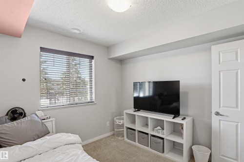 The room features a window with blinds, carpeted flooring, and a white paneled door - 115 6925 199 Street, Edmonton, AB - Indoor Photo Showing Other Room