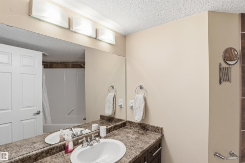 Bathroom featuring a vanity with a white sink, chrome faucet, and a large mirror - 115 6925 199 Street, Edmonton, AB - Indoor Photo Showing Bathroom