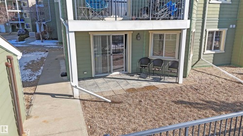The property features a ground-level patio with paving stones, an exterior light fixture, and a sliding glass door - 115 6925 199 Street, Edmonton, AB - Outdoor With Exterior
