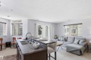 The open-concept living area features a kitchen island with a double sink and breakfast bar seating, carpeted flooring in the living room, and a sliding glass door providing external access - 115 6925 199 Street, Edmonton, AB  - Indoor 