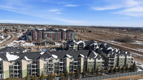 The property is a low-rise condominium building featuring balconies, a dark roof, and a pale green and beige exterior - 115 6925 199 Street, Edmonton, AB - Outdoor