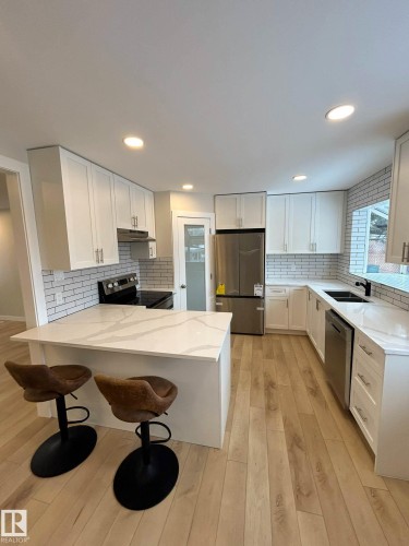 The kitchen features light-toned hardwood flooring, white cabinetry, and white countertops with natural stone veining - 56 Salisbury Avenue, St. Albert, AB - Indoor Photo Showing Kitchen With Upgraded Kitchen