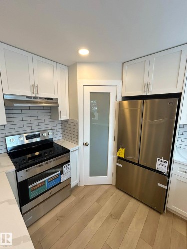 The kitchen features hardwood flooring, white cabinetry, and stainless steel appliances - 56 Salisbury Avenue, St. Albert, AB - Indoor Photo Showing Kitchen