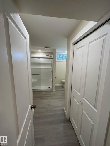 A bright hallway featuring light-colored flooring, white doors, and recessed lighting, leading to a bathroom with a shower and a window - 56 Salisbury Avenue, St. Albert, AB - Indoor Photo Showing Other Room