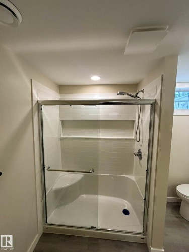 Shower with a sliding glass door, integrated seating, and tiled walls with built-in shelving - 56 Salisbury Avenue, St. Albert, AB - Indoor Photo Showing Bathroom