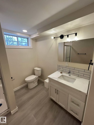 Well-appointed bathroom featuring a modern vanity with a white countertop and subway tile backsplash, a toilet, and a window providing natural light - 56 Salisbury Avenue, St. Albert, AB - Indoor Photo Showing Bathroom