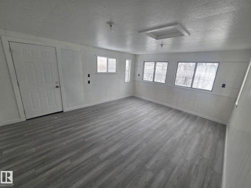 The room features light gray wood-look flooring, white paneled walls, and a white paneled door - 56 Salisbury Avenue, St. Albert, AB - Indoor Photo Showing Other Room