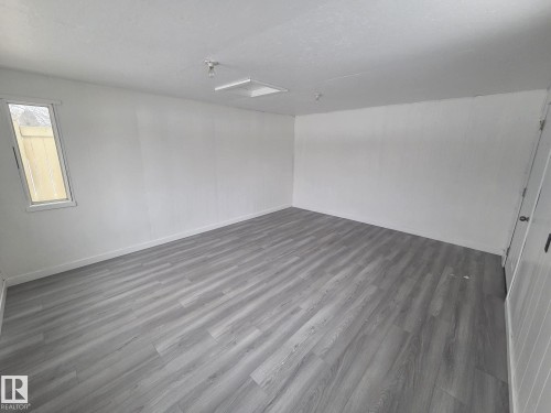 This versatile room features light grey wood-look flooring, white walls, and a window providing natural light - 56 Salisbury Avenue, St. Albert, AB - Indoor Photo Showing Other Room
