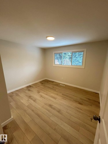 Room featuring light wood-style flooring, a window offering a view of greenery, and a ceiling light fixture - 56 Salisbury Avenue, St. Albert, AB - Indoor Photo Showing Other Room