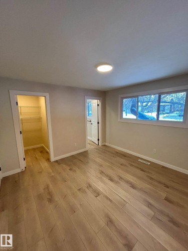 Room featuring light wood-style flooring, a recessed ceiling light fixture, a window with a view of trees, and an open closet with wire shelving and a 3 piece en suite bathroom. - 56 Salisbury Avenue, St. Albert, AB - Indoor Photo Showing Other Room