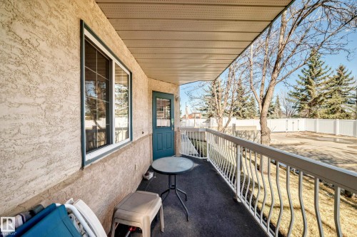 The property features a covered balcony with a white railing, a window, and an exterior door - 112 17150 94A Avenue, Edmonton, AB - Outdoor With Exterior
