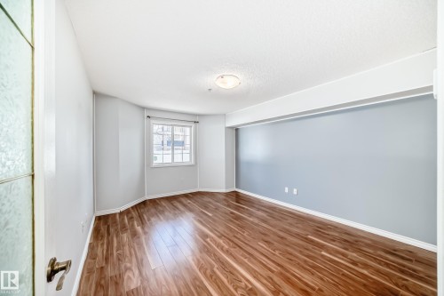 Bright room featuring rich wood flooring, light-colored walls, and a window with white trim - 112 17150 94A Avenue, Edmonton, AB - Indoor Photo Showing Other Room