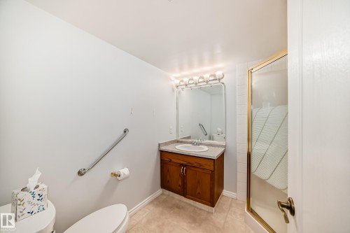 Bathroom featuring a wooden vanity with a countertop, a sink, and a mirror with overhead lighting - 112 17150 94A Avenue, Edmonton, AB - Indoor Photo Showing Bathroom