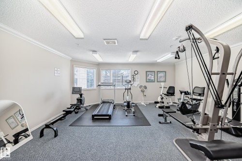 The property features an exercise room with various equipment, including a treadmill, stationary bikes, and a rowing machine - 112 17150 94A Avenue, Edmonton, AB - Indoor Photo Showing Gym Room