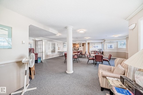 The property features a spacious common area with carpeted flooring, decorative wall sconces, and recessed lighting - 112 17150 94A Avenue, Edmonton, AB - Indoor