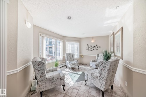 This bright room features tiled flooring and ample natural light from the large windows - 112 17150 94A Avenue, Edmonton, AB - Indoor Photo Showing Other Room