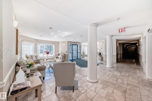 The property features a lobby area with tiled flooring, white columns, and large windows that provide natural light - 112 17150 94A Avenue, Edmonton, AB - Indoor Photo Showing Other Room