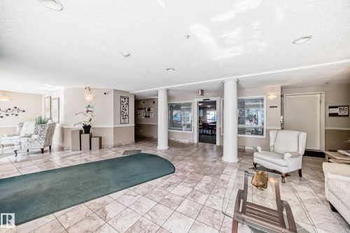 The inviting lobby features tiled flooring, decorative wall sconces, and structural columns - 112 17150 94A Avenue, Edmonton, AB - Indoor Photo Showing Living Room