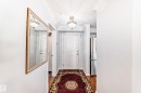 Entryway featuring wood floors, crown molding, a decorative ceiling light fixture, and a white paneled door - 112 17150 94A Avenue, Edmonton, AB  - Indoor Photo Showing Other Room 