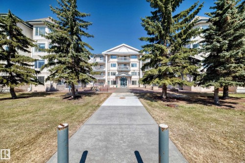 The property features a multi-story building with a light-colored exterior and balconies - 112 17150 94A Avenue, Edmonton, AB - Outdoor