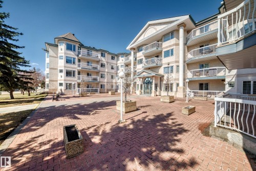 The property features a brick exterior with white trim and balconies, set against a clear sky - 112 17150 94A Avenue, Edmonton, AB - Outdoor