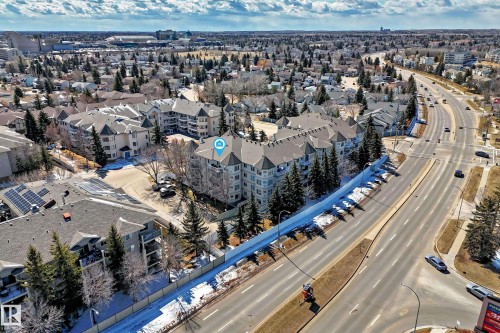 An aerial view showcasing the property's location within a developed neighborhood, featuring a multi-story building with a distinctive turret design - 112 17150 94A Avenue, Edmonton, AB - Outdoor With View