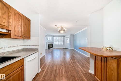 The kitchen features wood cabinetry, a built-in dishwasher, and a sink with a dark finish - 112 17150 94A Avenue, Edmonton, AB - Indoor Photo Showing Kitchen