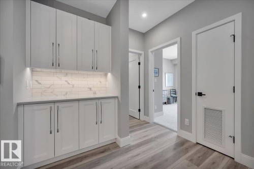 BAR AREA ADJACENT TO THE KITCHEN AND DINING AREA WITH QUARTZ COUNTER AND UNDER CABINET LIGHTING - 404 7463 May Common Nw, Edmonton, AB - Indoor Photo Showing Other Room