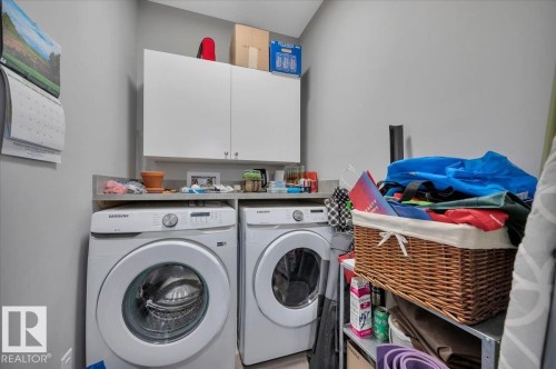 LARGE LAUNDRY ROOM WITH GRANITE COUNTER AND STORAGE CABINETS - 404 7463 May Common Nw, Edmonton, AB - Indoor Photo Showing Laundry Room