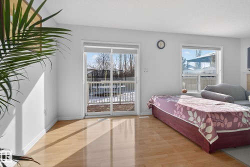 The living area features light hardwood flooring, a sliding glass door leading to an outdoor space, and windows that provide natural light - 421 84 Street, Edmonton, AB - Indoor Photo Showing Bedroom