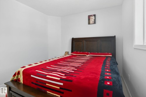 The property features a bedroom with a dark wooden bed frame and a window providing natural light - 421 84 Street, Edmonton, AB - Indoor Photo Showing Bedroom