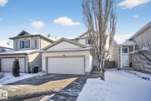 The property features a two-story design with light-colored siding, a front-facing garage, and a concrete driveway - 421 84 Street, Edmonton, AB - Outdoor With Facade