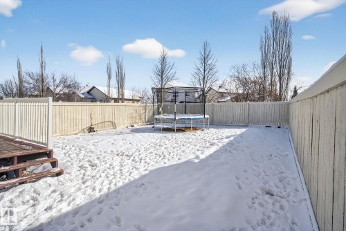 The property features a fenced backyard with a wooden deck and a snow-covered lawn - 421 84 Street, Edmonton, AB - Outdoor