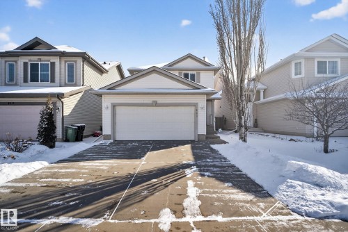 The property features a two-story home with light-colored siding, a front-facing attached garage, and a concrete driveway - 421 84 Street, Edmonton, AB - Outdoor With Facade