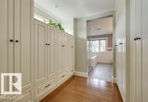 Walkway featuring hardwood flooring, built-in cabinetry with dark hardware, and a clear glass shower enclosure - 10836 130 Street, Edmonton, AB - Indoor Photo Showing Other Room