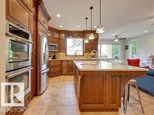 Kitchen featuring wood cabinetry, stainless steel appliances, a center island with a sink, and tiled flooring - 10836 130 Street, Edmonton, AB - Indoor Photo Showing Kitchen With Upgraded Kitchen