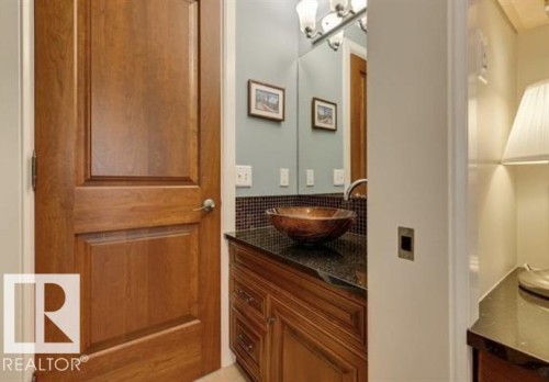 Bathroom vanity featuring a vessel sink, dark countertop, and mosaic tile backsplash - 10836 130 Street, Edmonton, AB - Indoor Photo Showing Bathroom