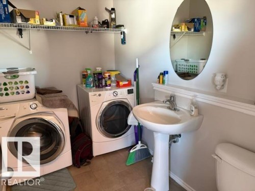 Dedicated laundry area featuring a washer and dryer, a pedestal sink with a chrome faucet, and a wall-mounted mirror - 21316 95 Avenue, Edmonton, AB - Indoor Photo Showing Laundry Room