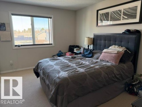 This bedroom features a large window providing ample natural light, neutral colored walls, and carpeting - 21316 95 Avenue, Edmonton, AB - Indoor Photo Showing Bedroom