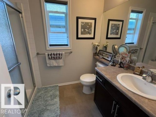 Bathroom featuring a vanity with an integrated sink, a mirror, and a window providing natural light - 21316 95 Avenue, Edmonton, AB - Indoor Photo Showing Bathroom