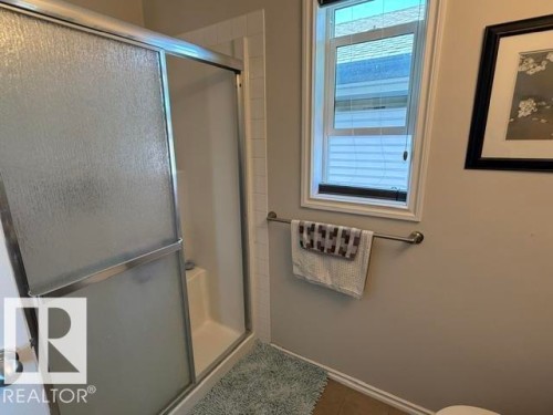 The bathroom features a shower with a sliding glass door, a window with blinds, and a towel bar - 21316 95 Avenue, Edmonton, AB - Indoor Photo Showing Bathroom
