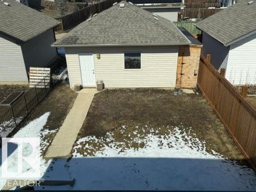 Detached outbuilding with light-colored siding, a gray shingle roof, and a white door with an exterior light fixture - 21316 95 Avenue, Edmonton, AB - Outdoor With Exterior