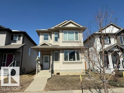 The property features a multi-story exterior with light-colored siding, a covered front porch, and a concrete walkway leading to the front entrance - 21316 95 Avenue, Edmonton, AB - Outdoor With Facade