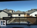 The property features a dark wood deck railing, a partially fenced yard with brown fencing, and a detached building with light-colored siding and a grey shingled roof - 21316 95 Avenue, Edmonton, AB  - Outdoor With Exterior 