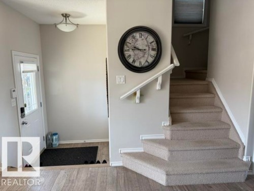 The property features a front entrance with a white door, a light fixture, and a staircase with carpeted steps and a white handrail - 21316 95 Avenue, Edmonton, AB - Indoor Photo Showing Other Room