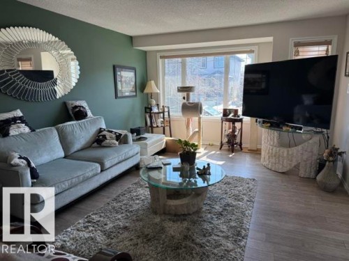 The living area features light-colored flooring, a large window providing natural light, and a prominent feature wall - 21316 95 Avenue, Edmonton, AB - Indoor Photo Showing Living Room