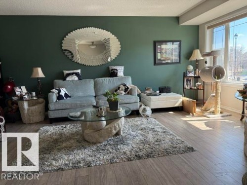 The living area features light-colored plank flooring and a dark green accent wall - 21316 95 Avenue, Edmonton, AB - Indoor Photo Showing Living Room