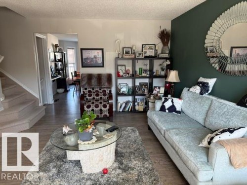 Living area featuring light wood-style flooring, a carpeted staircase, and a decorative wall mirror - 21316 95 Avenue, Edmonton, AB - Indoor Photo Showing Living Room