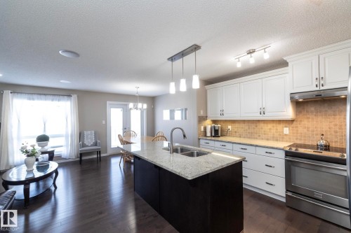 The kitchen features white cabinetry, a tiled backsplash, and stainless steel appliances - 132 Kirpatrick Way, Leduc, AB - Indoor Photo Showing Kitchen With Double Sink