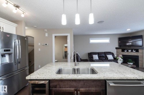 Spacious kitchen featuring a large island with a double stainless steel sink and granite countertops - 132 Kirpatrick Way, Leduc, AB - Indoor Photo Showing Kitchen With Double Sink With Upgraded Kitchen